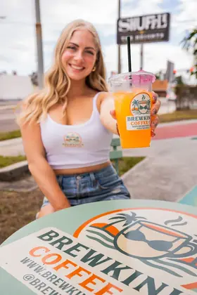 Customer at a BrewKini’s table holding an orange Wave Energy drink