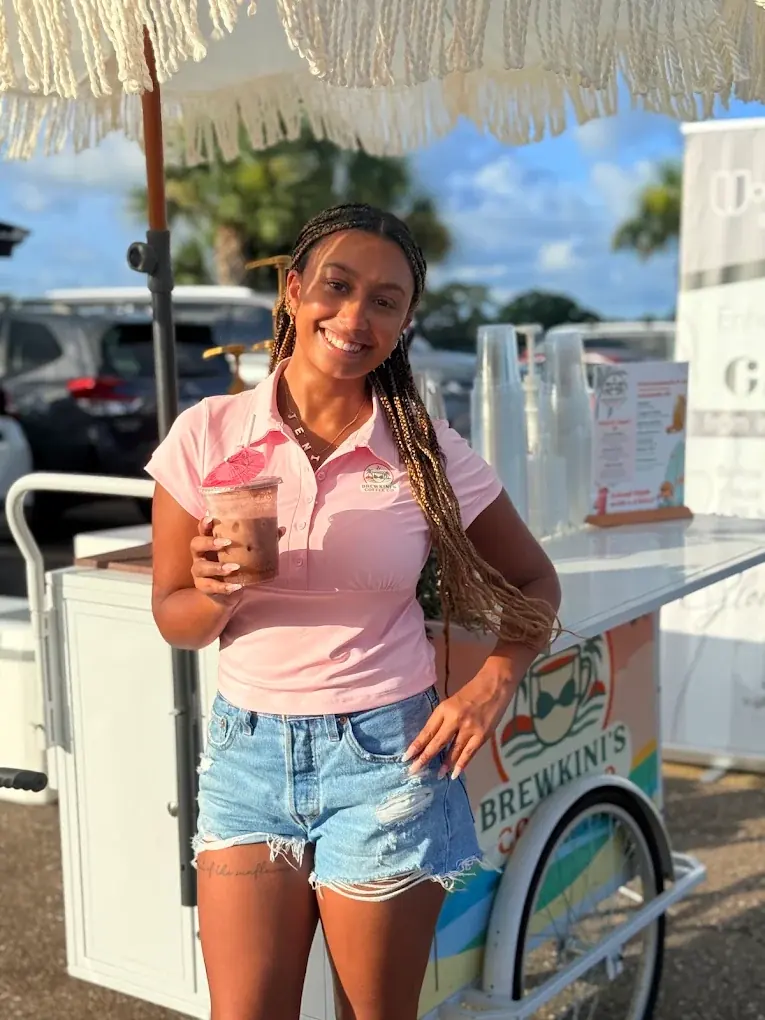 Barista in a pink polo next to the Coffee Bar Trike